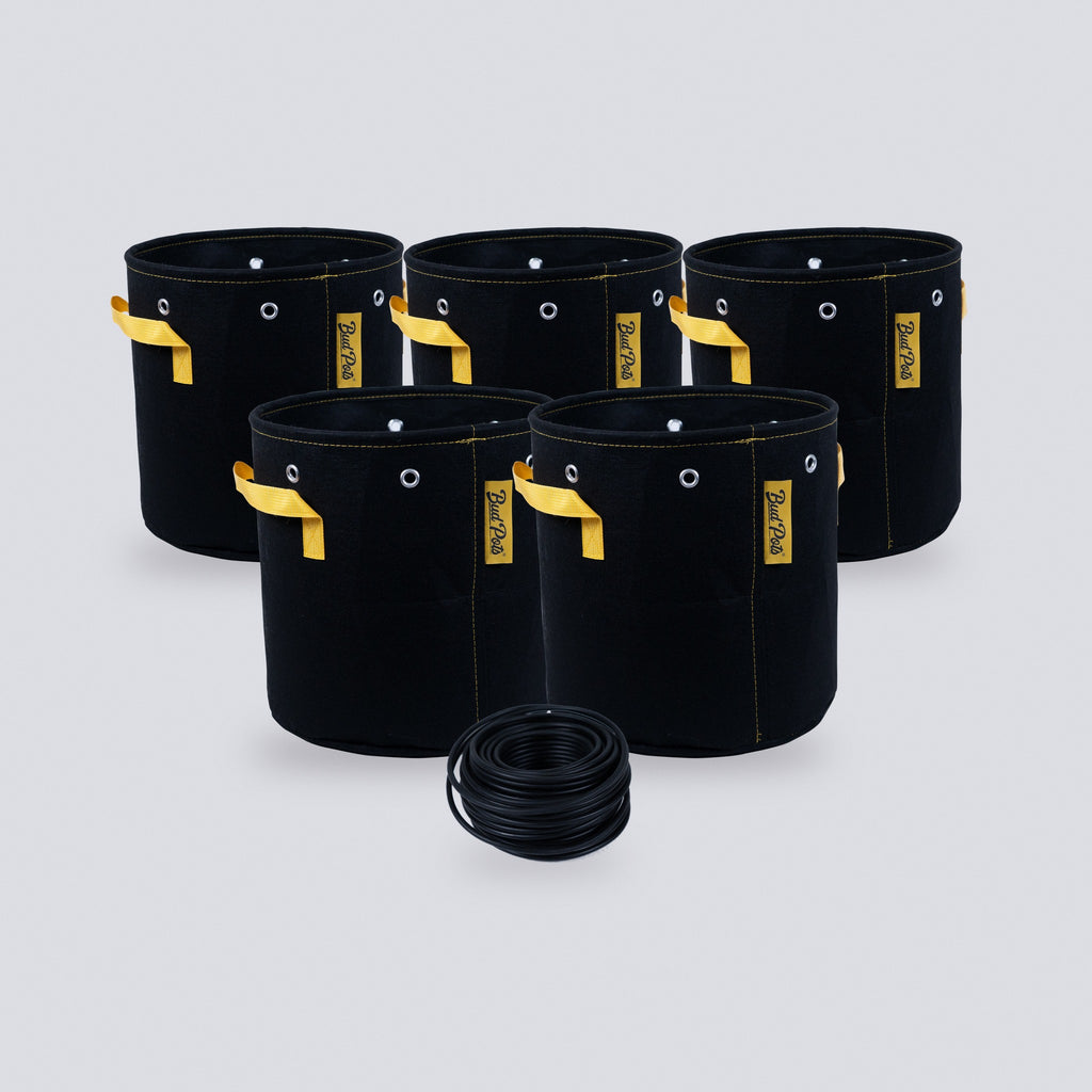 Five black 5 gallon fabric grow bags with yellow handles and a coil of black soft garden wire