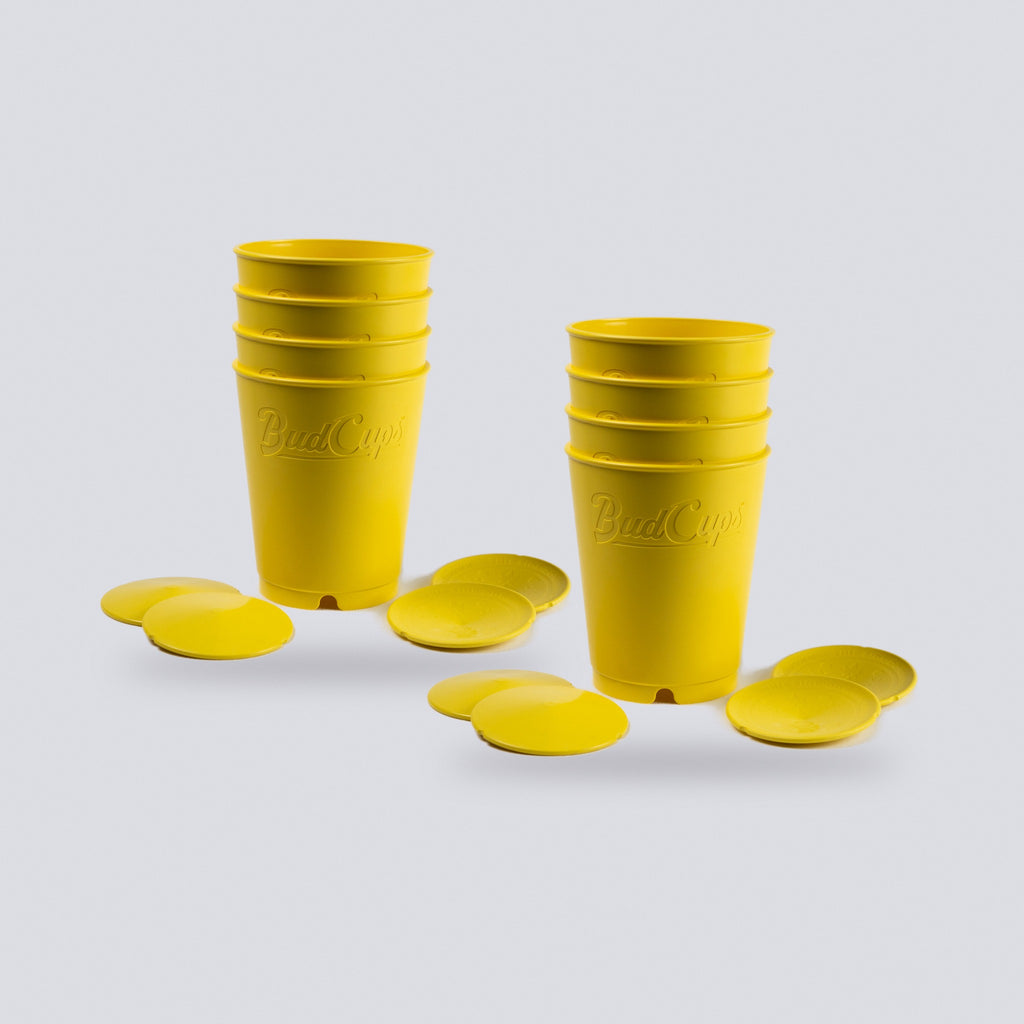 Two stacks of yellow seed starting cups with their bottom plates, ten cups in all