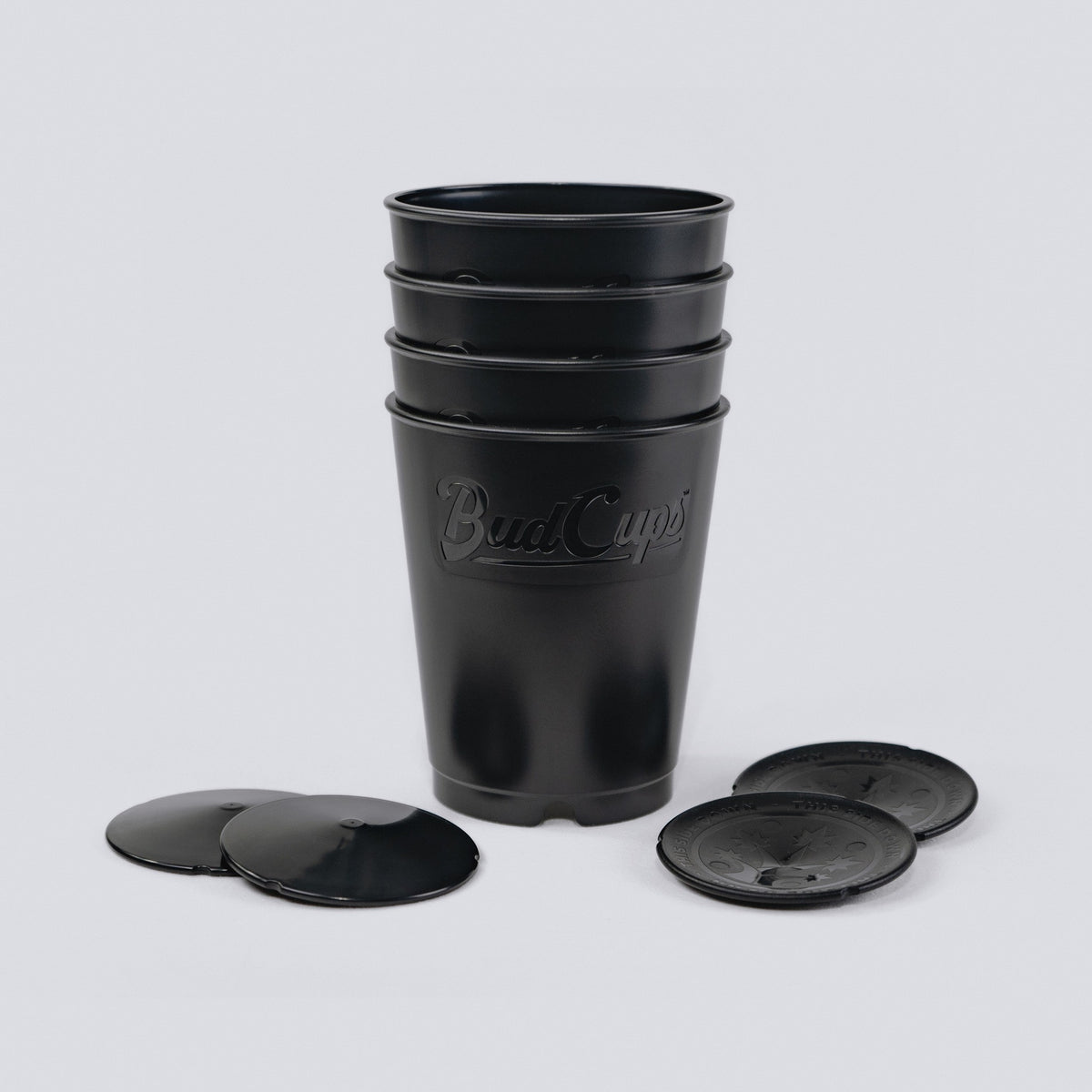 Black seed starting cups and their push-out bottom plates on a grey background