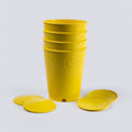 Yellow seed starting cups and their push-out bottom plates on a grey background
