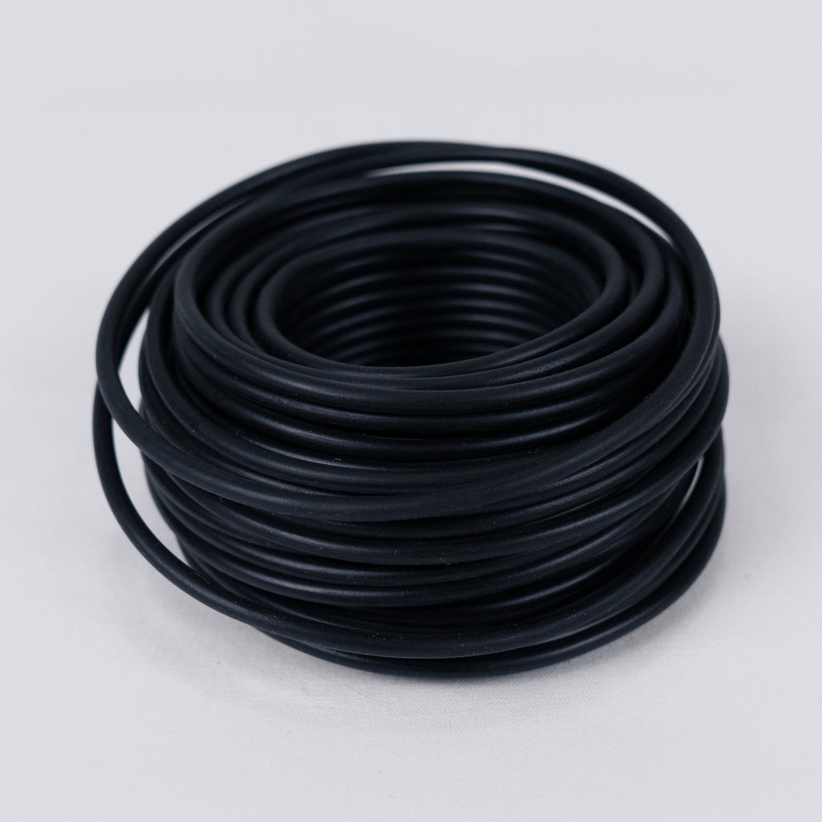 Coil of black soft garden wire on a grey background